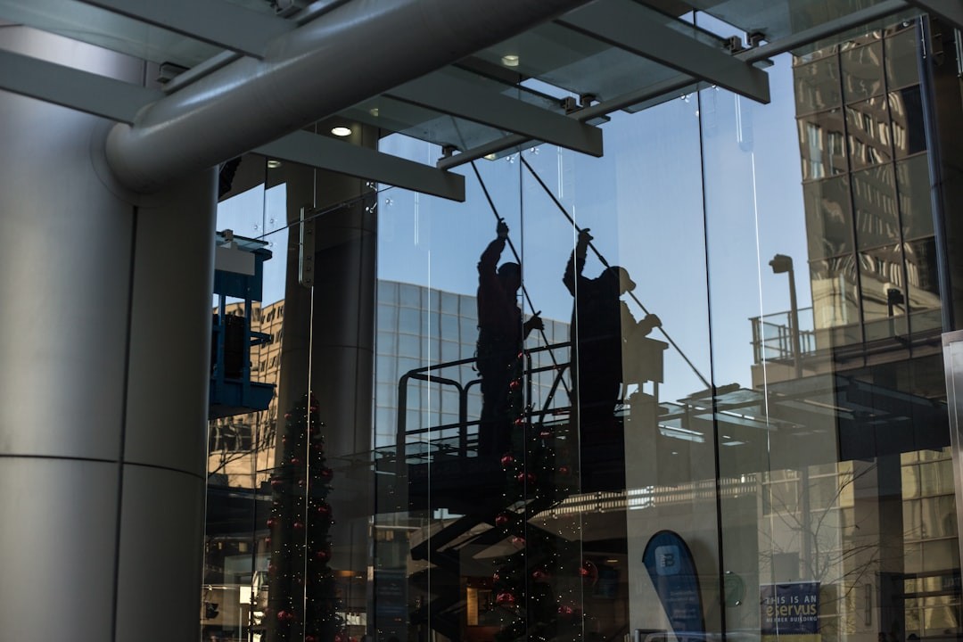 utility man standing in scissor platform cleaning glass window, indoor and outdoor windows, high level cleaning, ppe, h&, contract cleaning